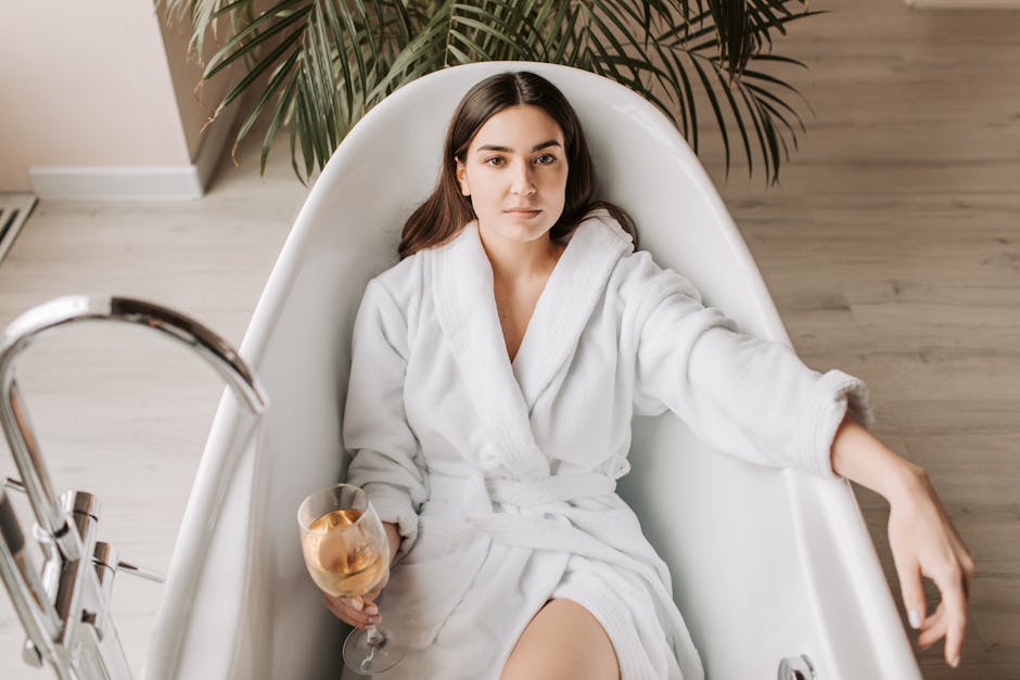 A woman in a white bathrobe enjoying a glass of wine in a stylish bathtub